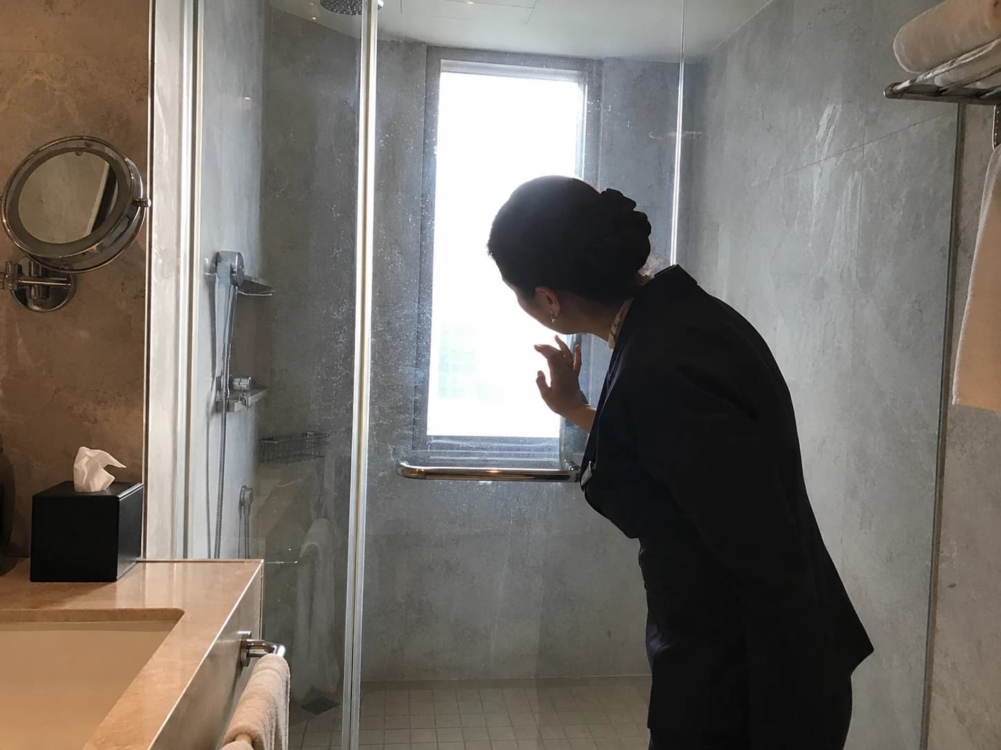 Gouvernante inspectant une salle de bain d'hôtel à contre-jour, révélant des traces invisibles sous éclairage normal