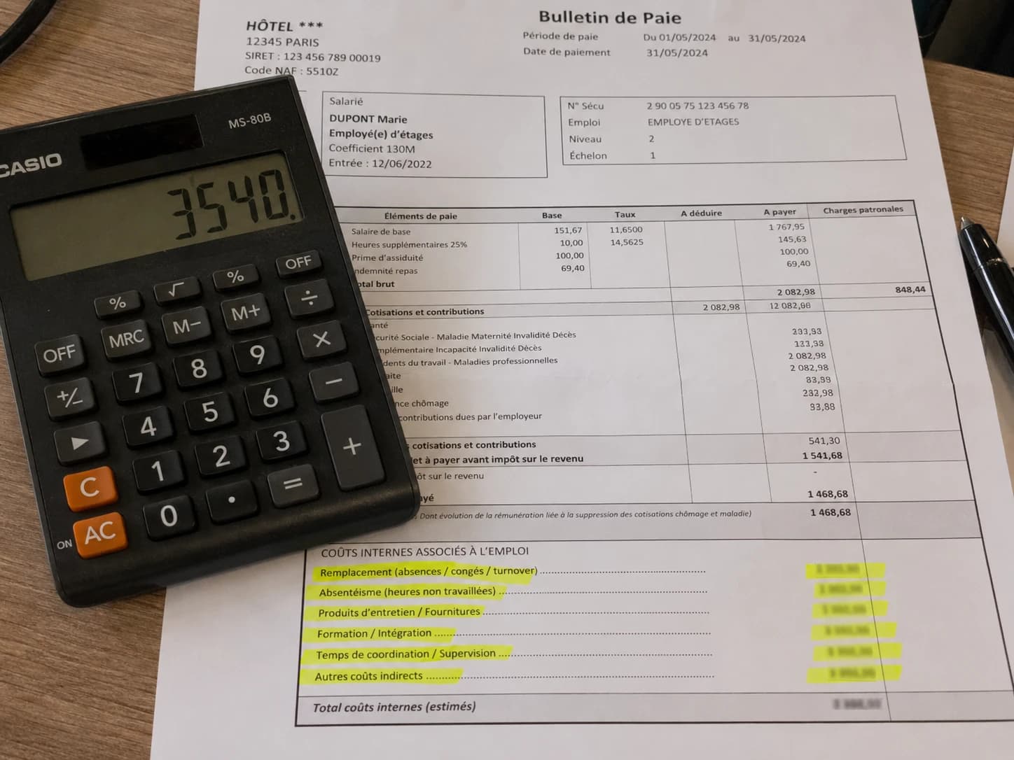 Calculatrice posée sur un bulletin de paie hôtelier avec des lignes de coûts masquées en surbrillance, illustrant les charges cachées du nettoyage en interne