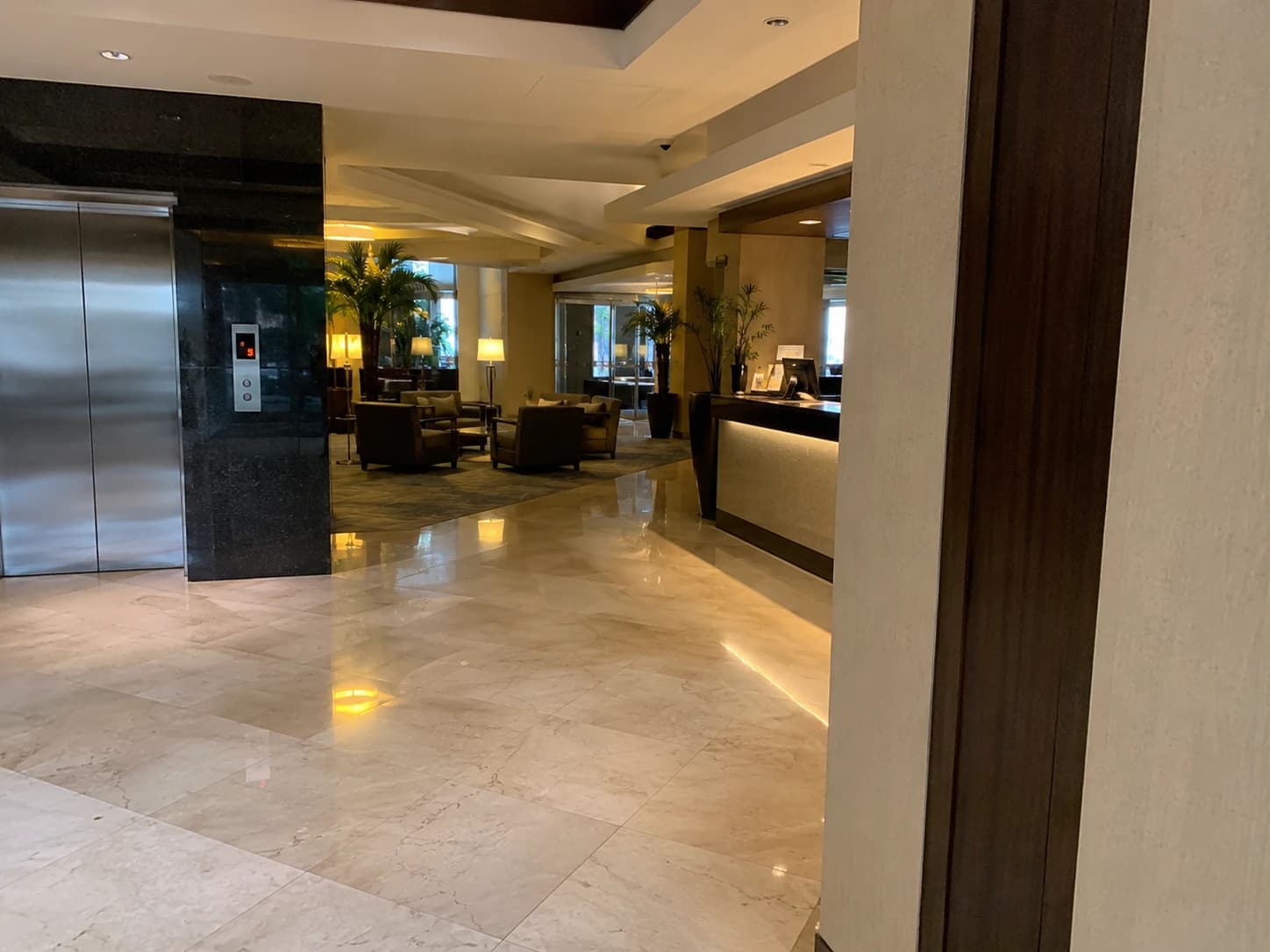 Hall de réception d'hôtel avec sol brillant, fauteuils de lobby et boutons d'ascenseur nettoyés, illustrant l'entretien des parties communes