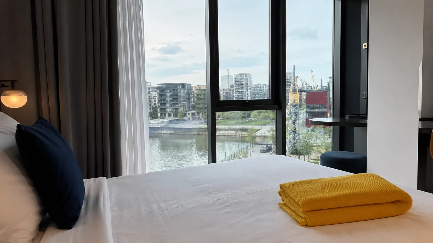 Chambre d'hôtel nantaise fraîchement préparée avec vue sur la Loire et l'île de Nantes, serviette jaune pliée sur le lit