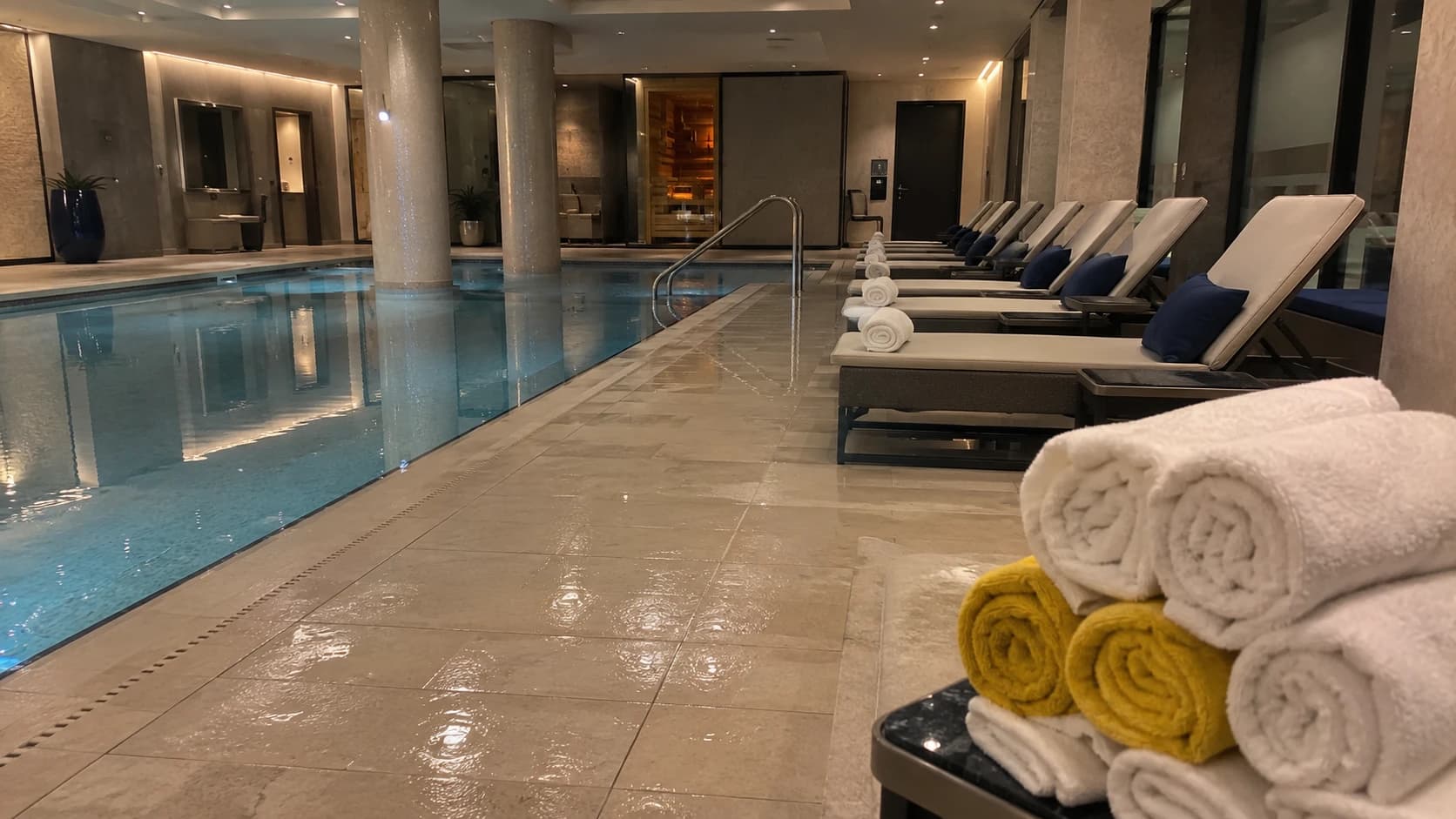 Bord de piscine intérieure d'hôtel impeccable, transats alignés et serviettes roulées, plage nettoyée avec touche de jaune sur le linge